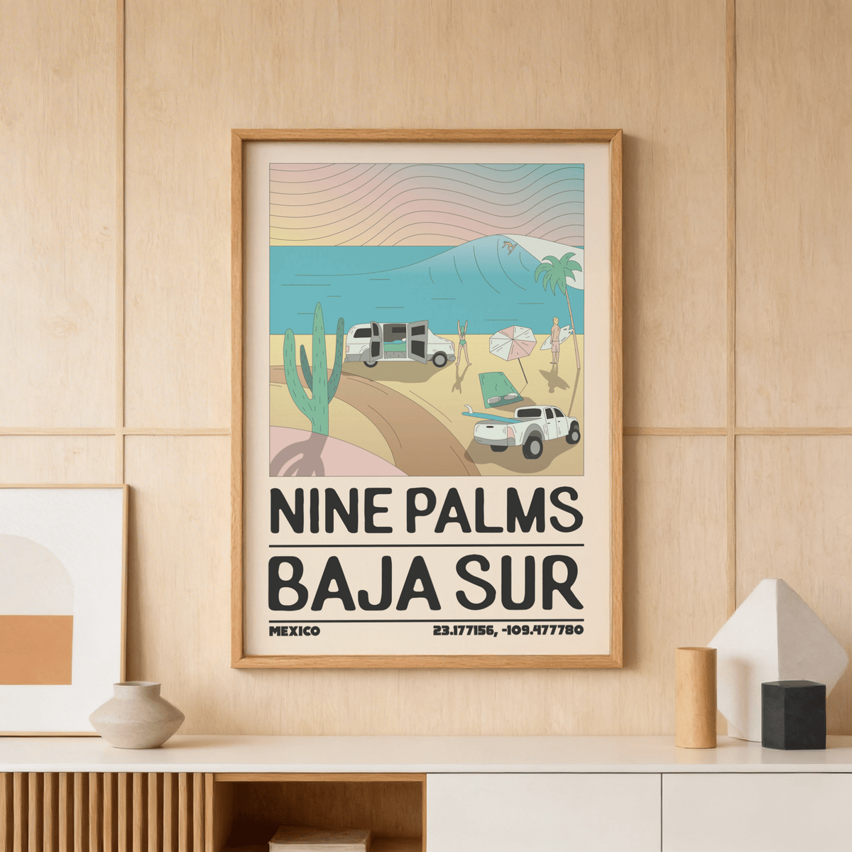 Framed Baja Sur wall art of a minimalist beach scene with waves on a wooden wall above a white sideboard with decor