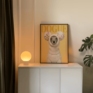 Funny dog wall art of a greyhound in a cream knit hat shown framed on a white cabinet with a lamp beside it