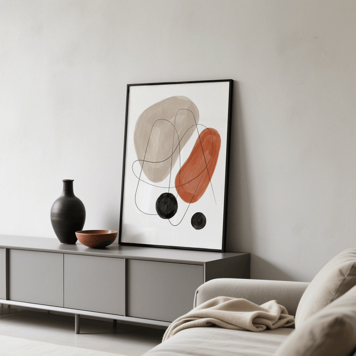 Abstract Shapes Art Print leaning on a grey sideboard with a black vase and bowl in a living room