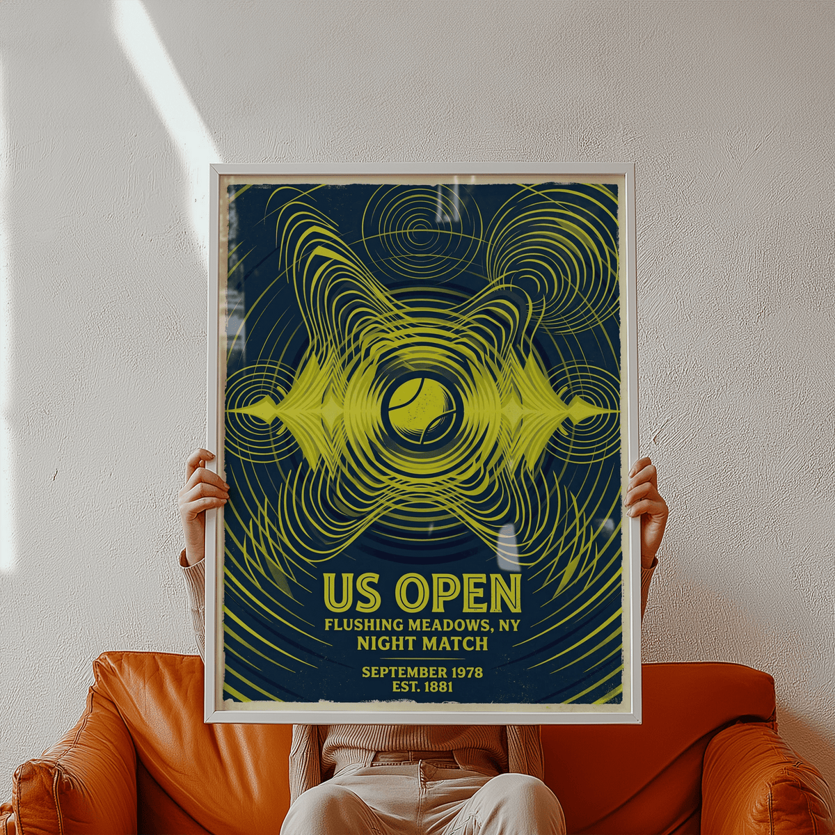 Framed Tennis Night Art Print held in front of a person on a brown leather sofa showing yellow abstract tennis ball design on dark
