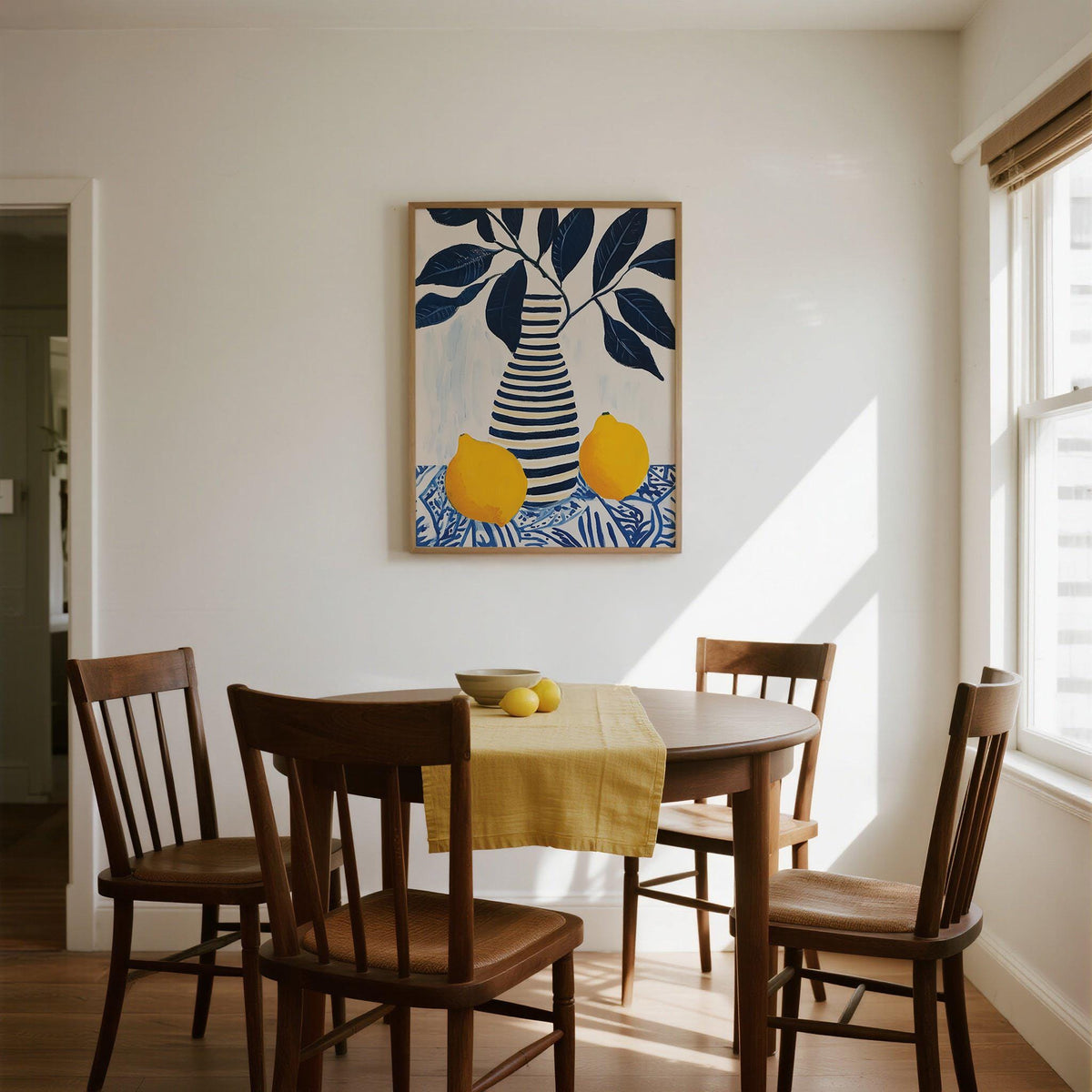 Lemon Art Print above a dining table with wooden chairs and a yellow table runner in natural light