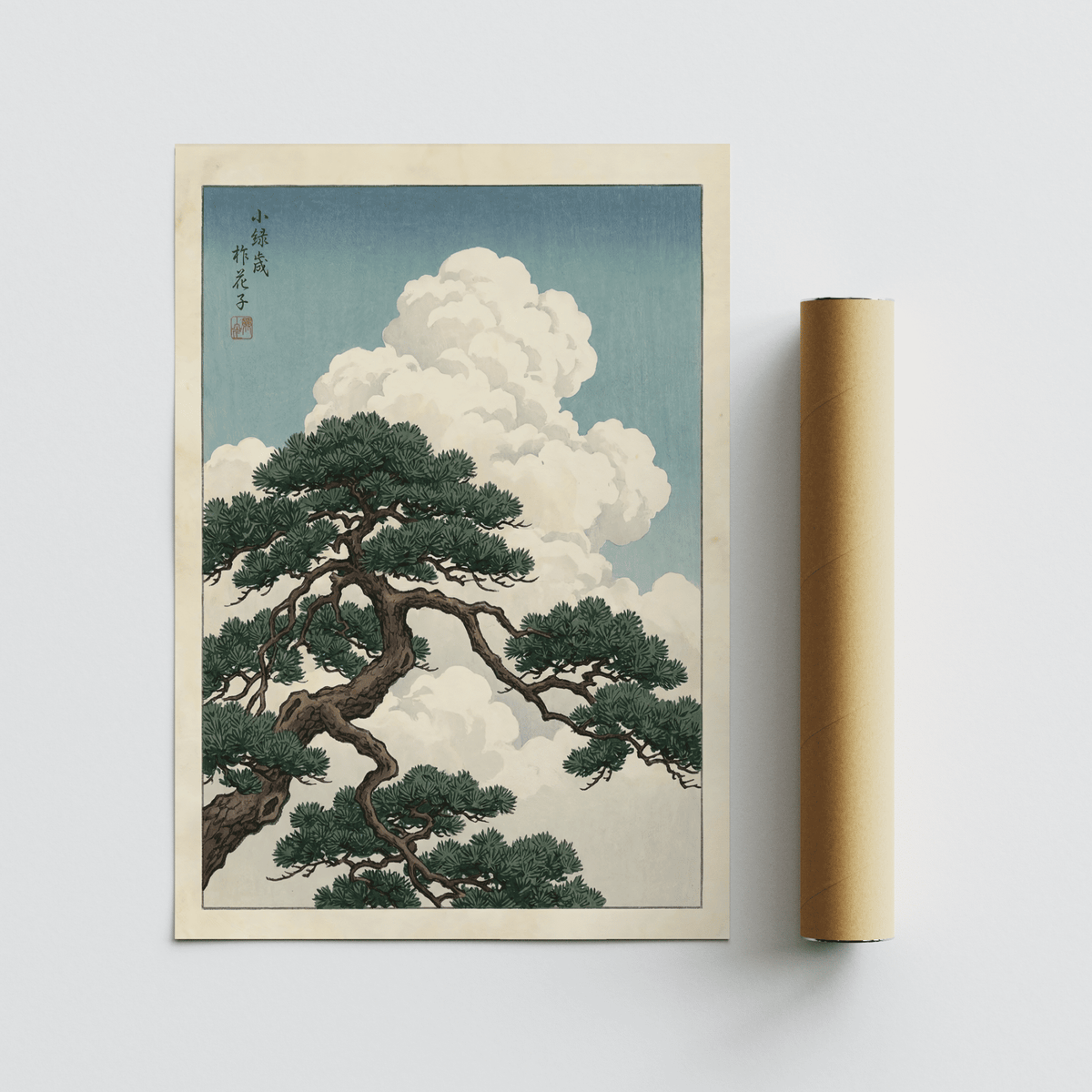 Japanese landscape poster with pine tree branch and white clouds next to a cardboard packaging tube
