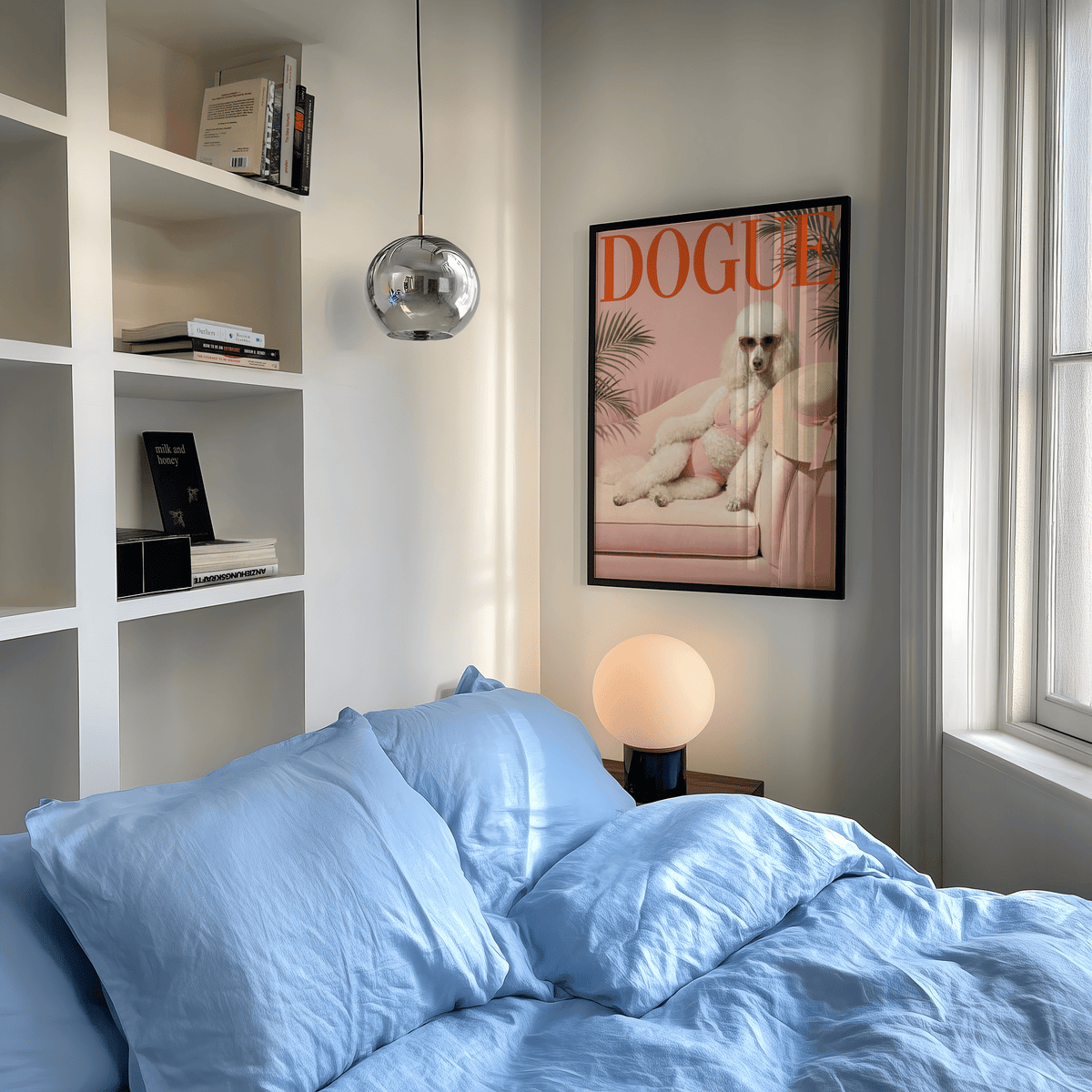 Pink Poodle Print framed on a bedroom wall above a lamp with blue bedding nearby