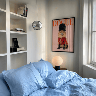 Pomeranian Poster Print of a dog in royal guard costume above a bedside lamp in a bedroom