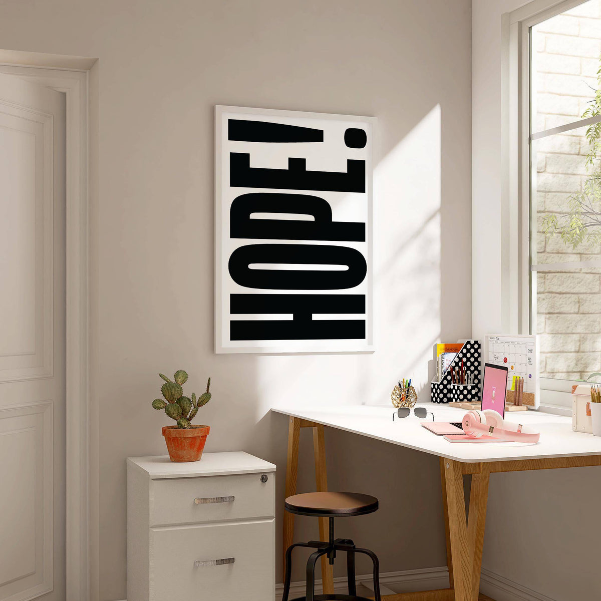 Motivational Work Posters print on a wall in a bright office with a cactus on a cabinet