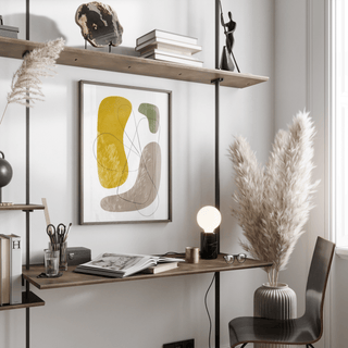 Modern Abstract Wall Art print with organic shapes in yellow, green and grey above a desk with lamp in a living space