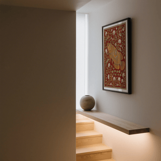 Traditional Indian wall art of a decorative fish with botanical elements in warm colours in a stairwell with a ceramic vase