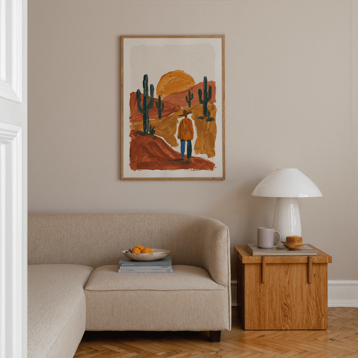 Desert Landscape Art Print hung above a beige sofa with a wooden side table and a white lamp