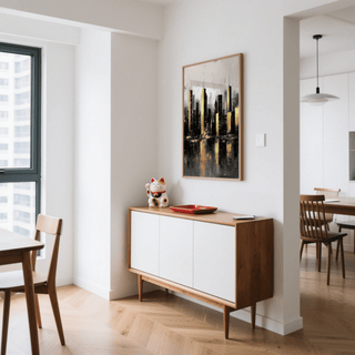 Gold and black skyline poster in a wooden frame above a mid-century modern sideboard with a lucky cat figure