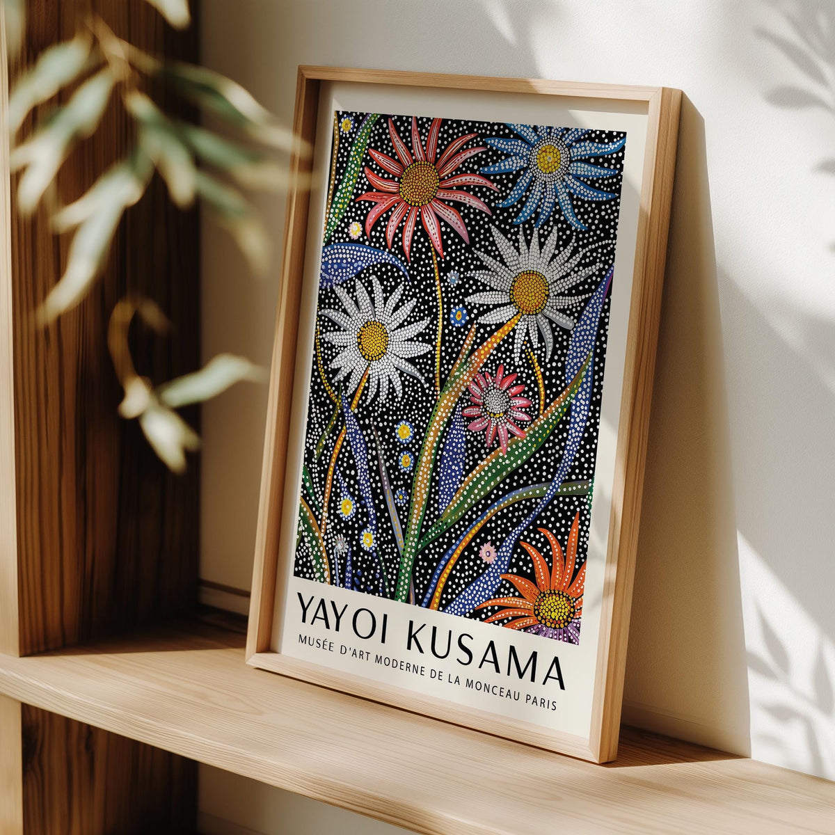 Framed close-up of abstract botanical wall art with dotted flowers in bright colours leaning on a wooden shelf