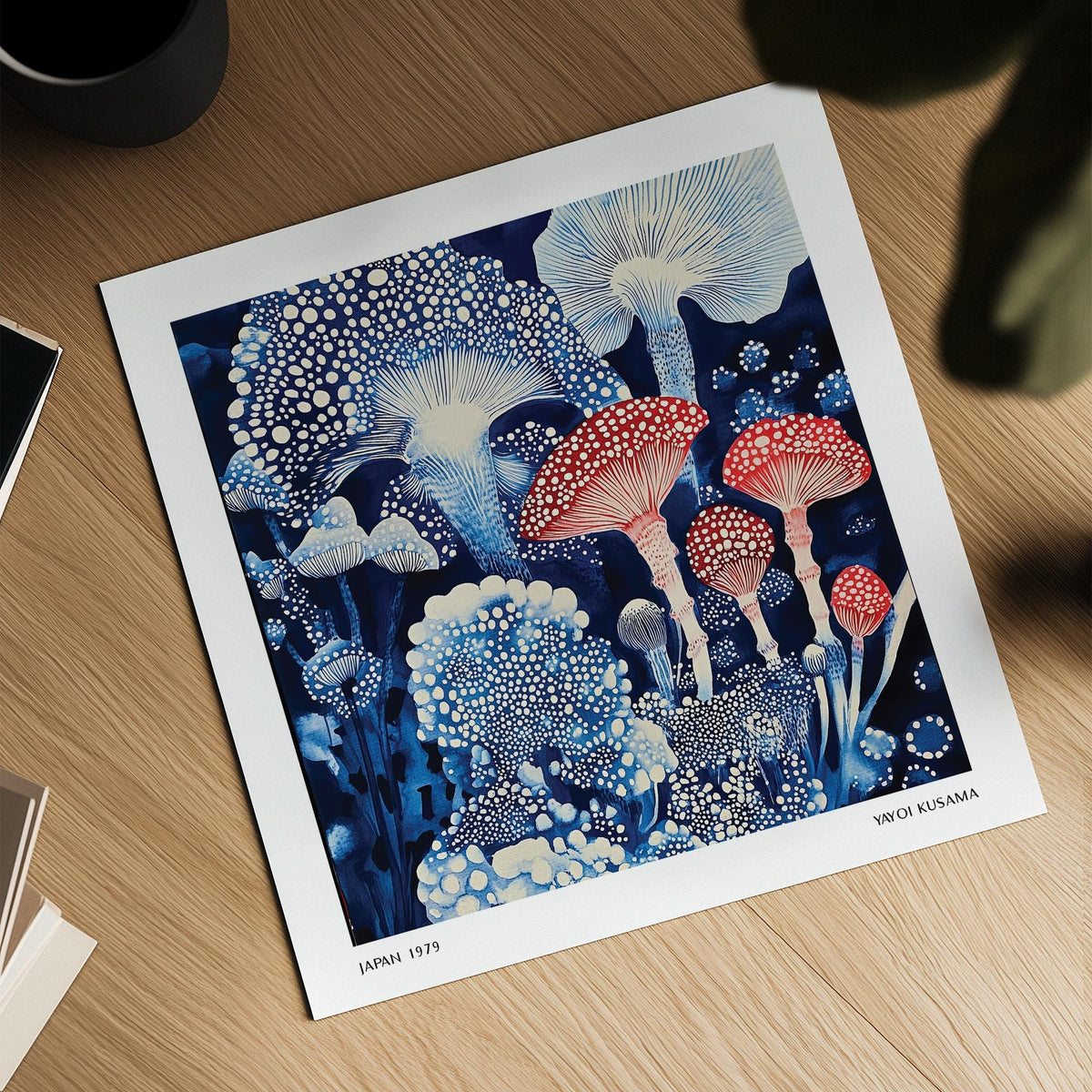Japanese Poster with blue and red toadstools on a wooden surface beside a black pot