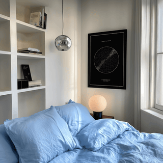 Custom Star Map print on a wall above a bedside table lamp in a light bedroom