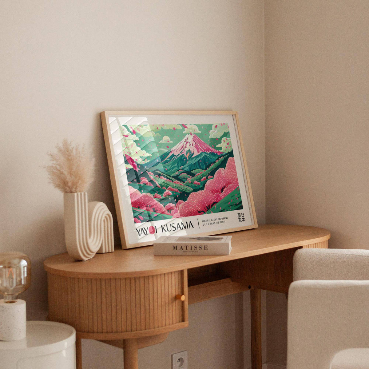 Cherry Blossom Art print leaning on a wooden desk with a decorative vase and book in a softly lit room