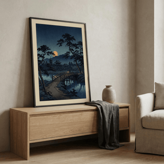 Moonlit Bridge art print leaning on a wooden sideboard with a ceramic vase beside it