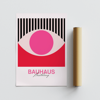 Abstract eye art poster with pink circle and black stripes leaning next to a rolled brown packaging tube