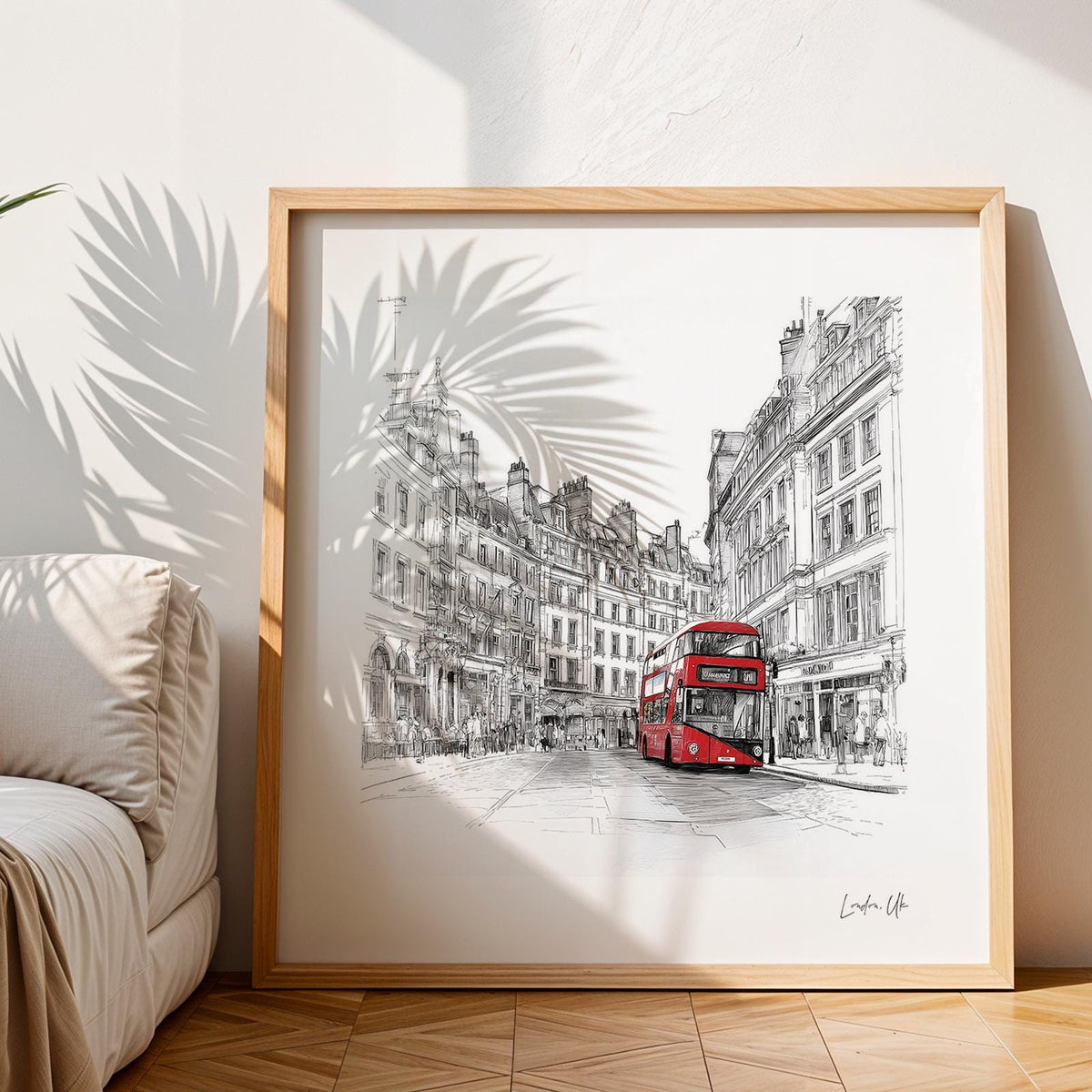 Framed London England wall art showing a red double-decker bus with detailed buildings and shadow of a plant