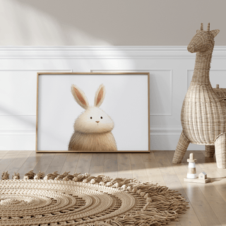Print leaning on a floor against a white wall featuring a fluffy rabbit illustration with light brown and white colours and a wicker
