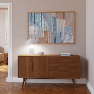 Pastel Blue And Pink Abstract Prints framed print with circles pattern above a wooden sideboard with a lamp in a lounge
