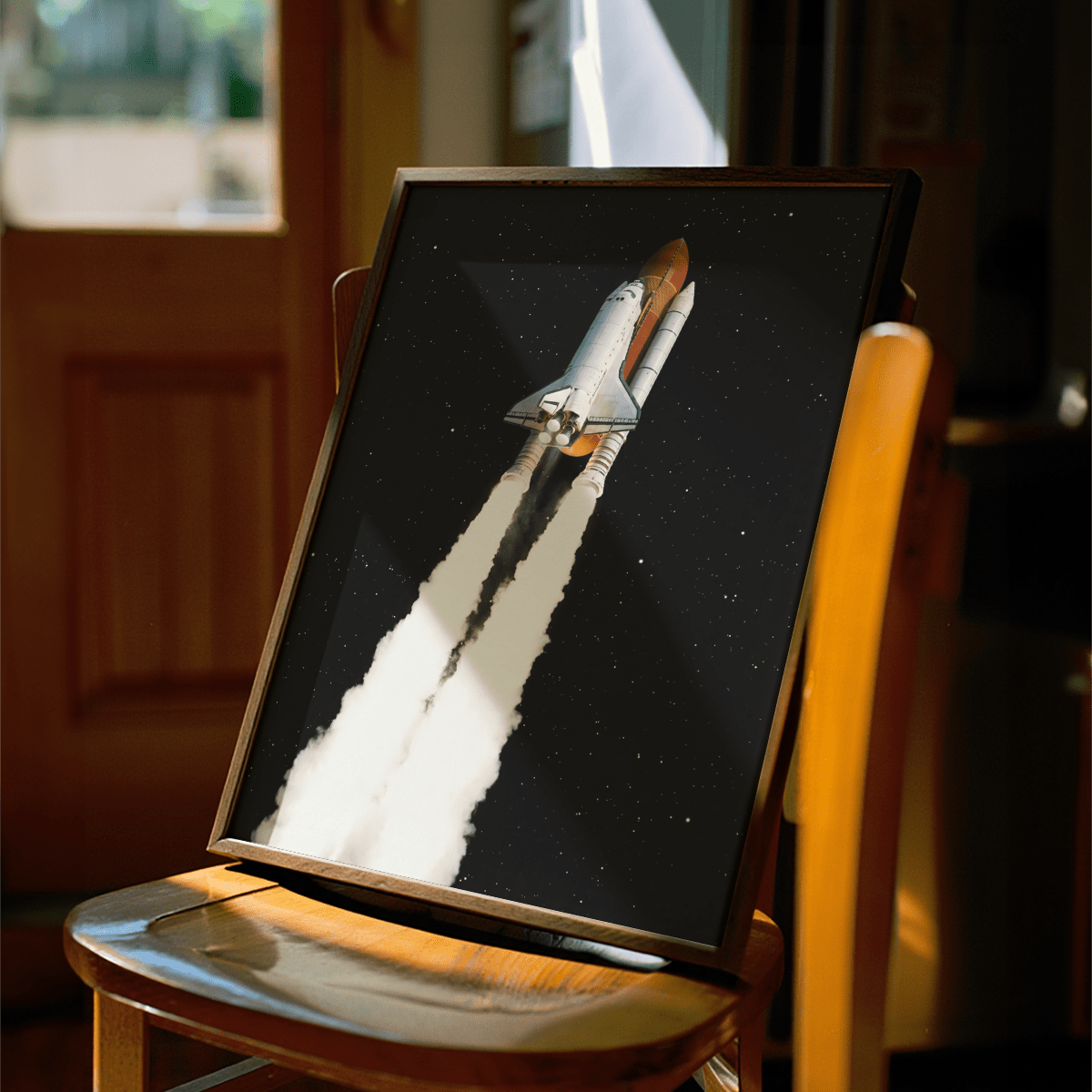 Framed Rocket Launch wall art with space shuttle and white smoke on a wooden chair