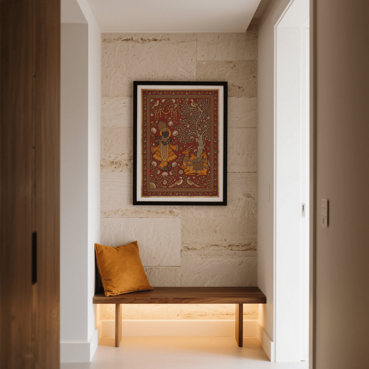 Indian Folk Art Print of Krishna playing flute with orange and brown tones hung above a bench with an orange cushion