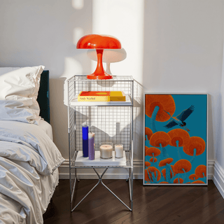 Print leaning on floor of Japandi bird print with crane and orange mushrooms next to bedside table