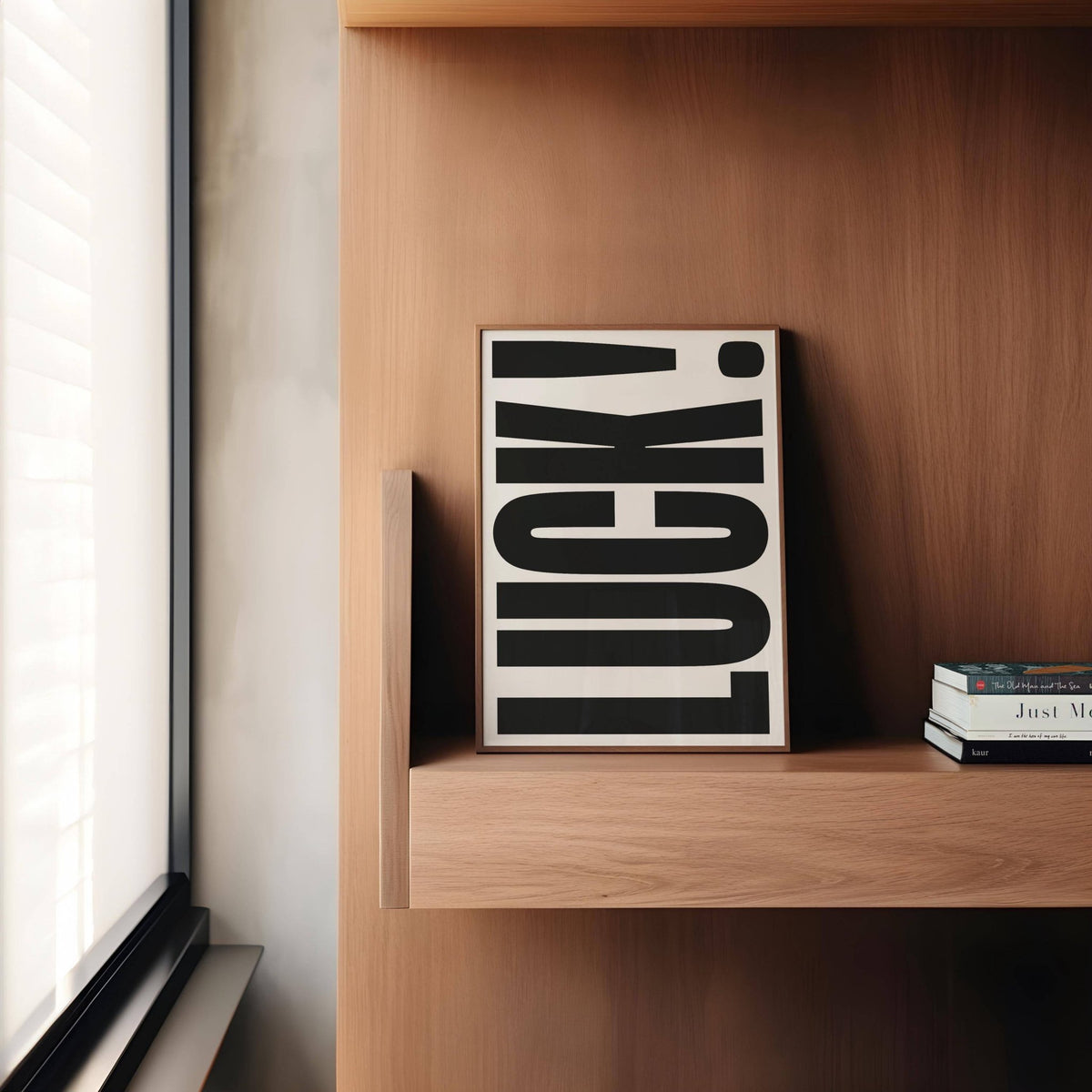Good Luck Print leaning on a wooden shelf with books beside it in natural light