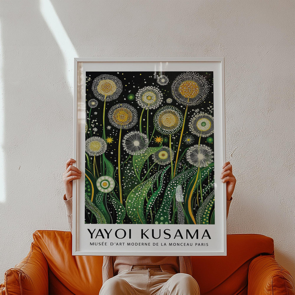 Framed Botanical Wall Art of golden dandelions with green leaves held above an orange sofa