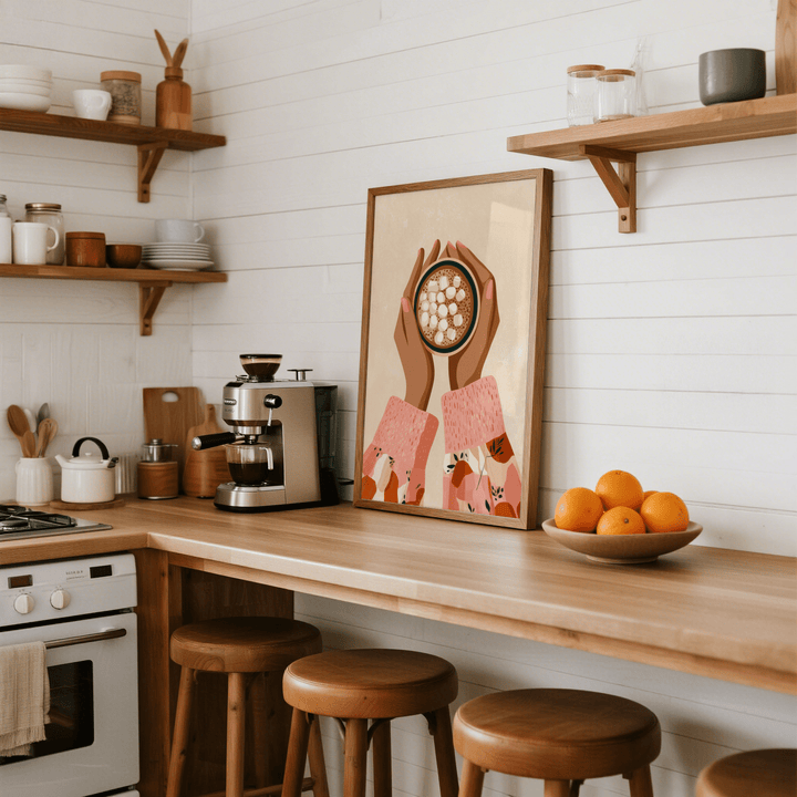 Hot Cocoa wall art leaning on a kitchen counter with a bowl of oranges and coffee machine