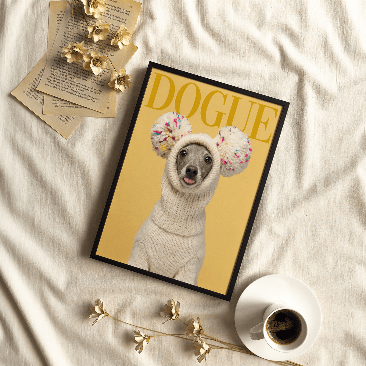 Framed print of a greyhound dog in a knit hat with large pom-poms on a mustard background with text above and a cup of coffee nearby
