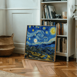 Starry Night art print leaning on wooden parquet floor next to a bookcase and woven basket