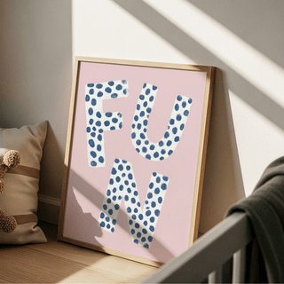 Fun typography wall art with blue polka dots on white letters against pink leaning on floor by a cushion
