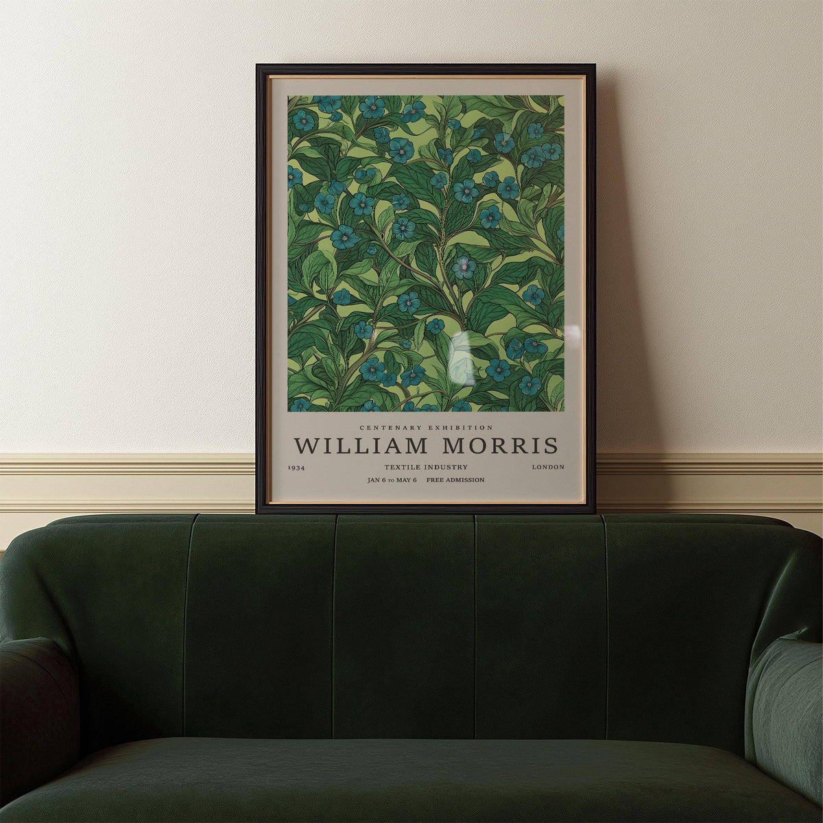 Green wall art for living room of blue flower branch and green leaves above a dark green sofa
