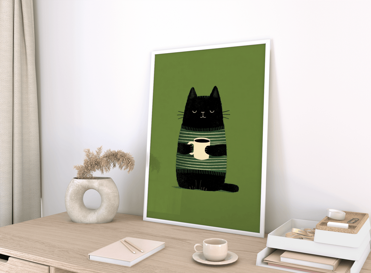 Print leaning on a shelf of Cat Coffee wall art with black cat holding a cream cup on green