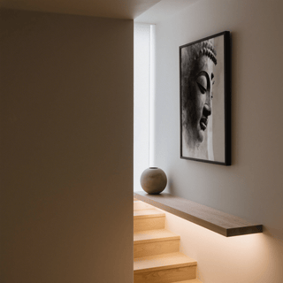 Zen Statue Face Art Print on wall in a stairwell with wooden steps and a round vase on a wooden shelf