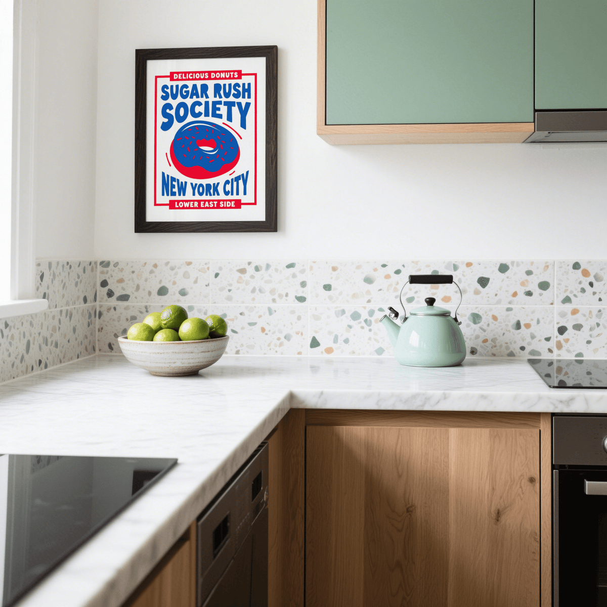 Donut wall art framed on a kitchen wall above a teal kettle and green apples