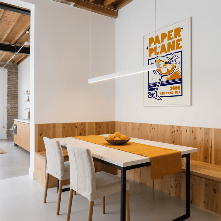 Paper Plane Cocktail Poster print on a wall with yellow and navy retro illustration in a dining area with a bowl of oranges