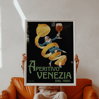 Framed Vintage Aperitivo Print of an apricot peel dancer holding a glass held above a brown leather sofa