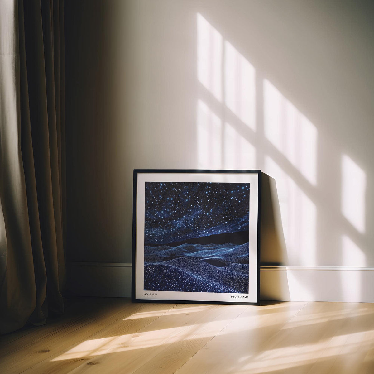 Framed navy blue artwork of a starry night sky with dunes leaning on a floor near curtains