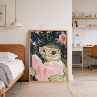Print leaning on floor of turtle reading art print with pink book and glasses near wooden bed