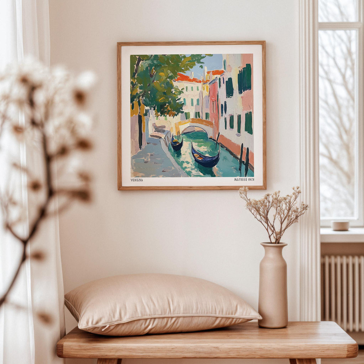 Venice wall art of gondolas and canal in warm colours framed above a table with a beige cushion and vase