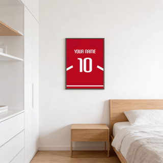 Football Shirt Poster in Red with White Sleeve Stripes on a bedroom wall above a wooden bedside table