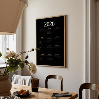 Modern Calendar Print on a wall with a wooden frame and black background in a dining room with a wooden table and lamp