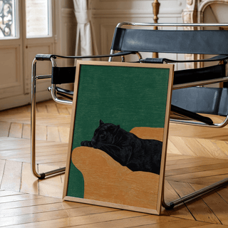 Big Cat Art Print leaning on floor by black and chrome chair in a room with wood floor