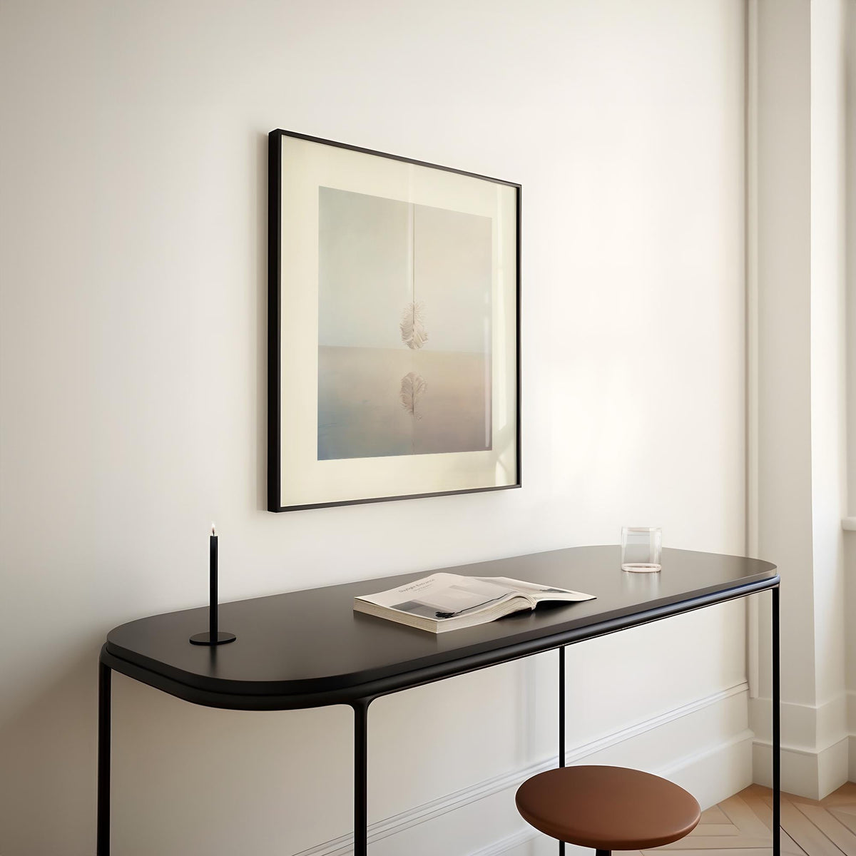 Surrealist Art for Sale wall art of a white feather above a reflective surface above a black console table with a candle and book
