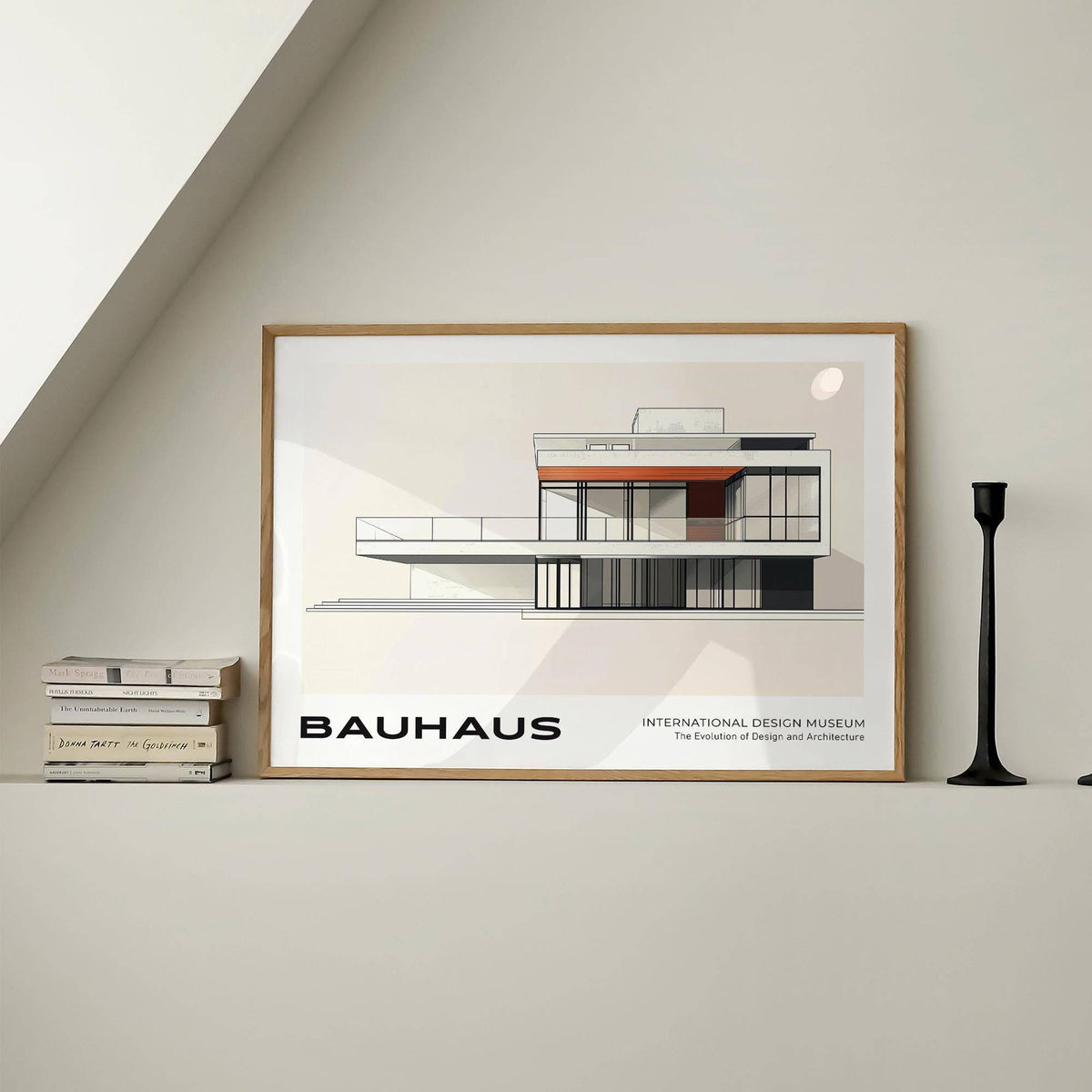 Framed architecture art print of a minimalist modernist building with cream and rust colours on a shelf beside stacked books