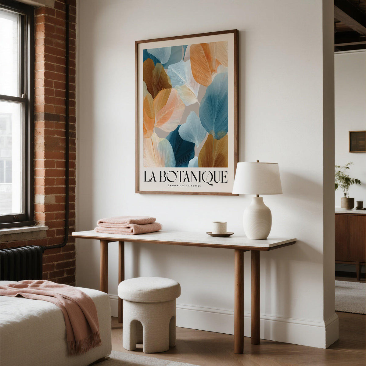 Flower Art for Walls framed print of abstract botanical leaves in warm and cool tones above a wooden table with a lamp in a bedroom