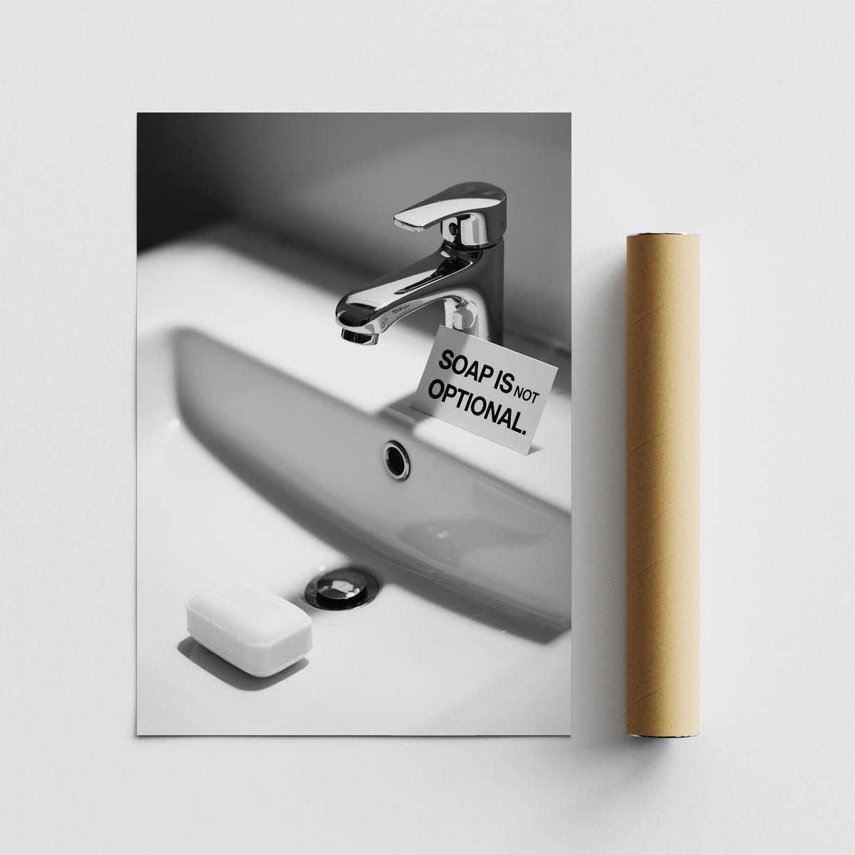 Print of a bathroom sink with a chrome tap and a soap bar beside a sign with black text on white