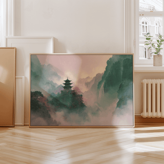 Print leaning on a floor with misty mountain temple in green and pink hues near a window with a plant on the sill