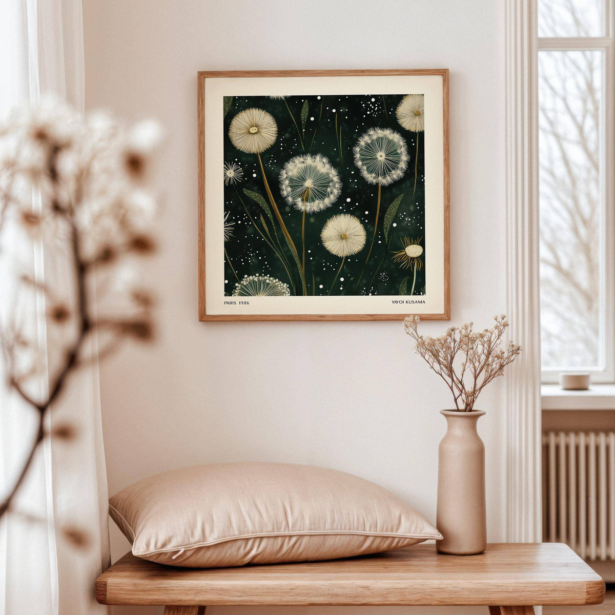 Square wall art of white dandelion seed heads in an illustration style above a wooden bench with a cushion