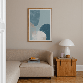 Abstract blue art print of calming abstract circles in blue and beige above a sofa in a lounge
